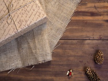 Vintage hediye kutusu, çam kozalakları, Noel oyuncak ahşap ve çuval bezi arka plan, fotoğraf üstten görünüm üzerinde. Metin için yer kopyalayın.