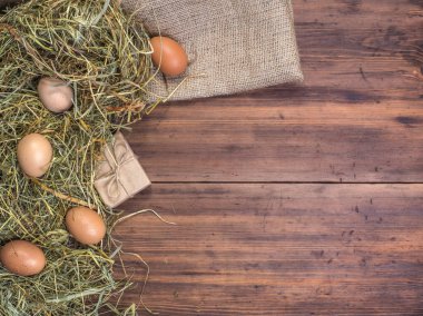 Kırsal çevre kahverengi tavuk yumurtası, hediye kutusu ve saman eski ahşap plakalar arka plan üzerinde arka plan. Üstten Görünüm. Paskalya kartları için yaratıcı arka plan