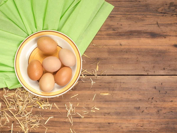 Fondo ecológico rural con huevos de pollo marrón, una pieza de arpillera y paja en el fondo de tablones de madera viejos. La vista desde arriba. Fondo creativo para tarjetas de Pascua — Foto de Stock