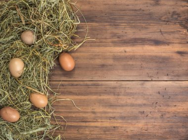 Kırsal çevre kahverengi tavuk yumurtası ve saman eski ahşap plakalar arka plan üzerinde arka plan. Üstten Görünüm. Paskalya kartları için yaratıcı arka plan