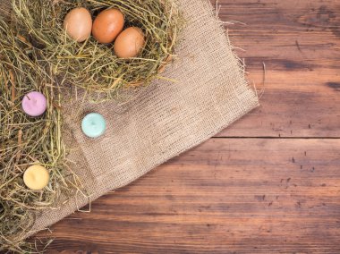 Kırsal çevre kahverengi tavuk yumurtası, renkli mumlar ve saman eski ahşap plakalar arka plan üzerinde arka plan. Üstten Görünüm. Paskalya kartları, menü, reklam için yaratıcı arka plan