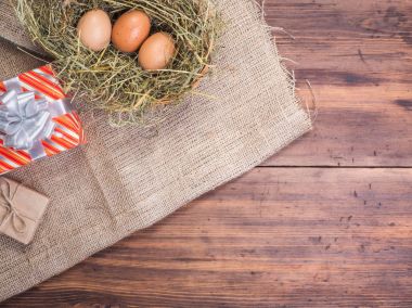 Kırsal çevre kahverengi tavuk yumurtası, hediye kutusu ve saman eski ahşap plakalar arka plan üzerinde arka plan. Üstten Görünüm. Paskalya kartları için yaratıcı arka plan