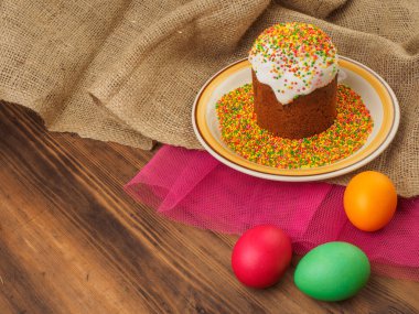 Paskalya kek, renkli tatlı tozu ve Paskalya ile seramik kase yumurta renkli. Rusça ve Ukraynaca, Ortodoks Slav geleneksel Paskalya kulich kırsal arka plan üzerinde. Eski ahşap, kırmızı örgü kağıt ve çuval bezi