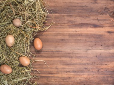 Kırsal çevre kahverengi tavuk yumurtası ve saman eski ahşap plakalar arka plan üzerinde arka plan. Üstten Görünüm. Paskalya kartları için yaratıcı arka plan