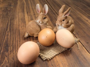 Paskalya tavşanları eski kurulları çuval bezi ve kahverengi tavuk yumurtası ile gelen ahşap masa arka plan üzerinde