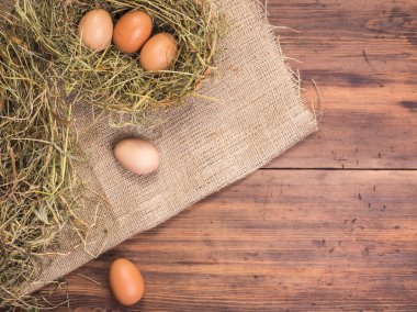 Kırsal çevre kahverengi tavuk yumurtası, çuval bezi ve saman eski ahşap plakalar arka plan üzerine bir parça ile arka plan. Üstten Görünüm. Paskalya kartları için yaratıcı arka plan