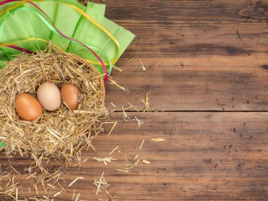 Kahverengi yumurta saman içinde iç içe. Kırsal çevre kahverengi tavuk yumurtası ve saman eski ahşap plakalar arka plan üzerinde arka plan. Üstten Görünüm. Paskalya kartları veya Restoran Menü yaratıcı arka plan
