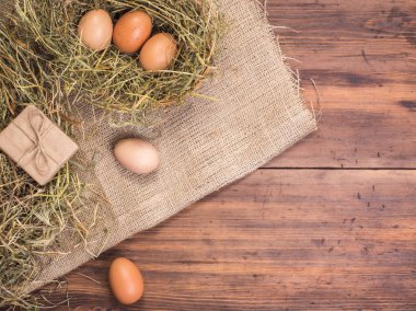 Kırsal çevre kahverengi tavuk yumurtası, hediye kutusu ve saman eski ahşap plakalar arka plan üzerinde arka plan. Üstten Görünüm. Paskalya kartları için yaratıcı arka plan