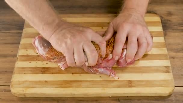 Um homem cozinha carne em uma tábua de corte na mesa de tábuas de madeira velhas. As mãos masculinas polvilhe temperos e esmigalhe um pedaço de carne. Cozinhar carne de porco, carne na cozinha. Vista de cima — Vídeo de Stock