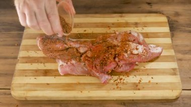 Bir adam eski ahşap plakalar tablosundan bir kesme tahtası üzerinde et yemek yapıyor. Erkek el baharat serpin ve bir et parçası çökmek. Domuz eti, yemek ev mutfak sığır. Görünümü en iyi