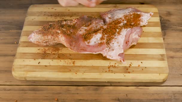 Az ember hús egy daraboló Board az asztalra a régi fa deszka a szakácsok. Férfi kezét Szórjuk a fűszereket, és a gyűrődő egy darab húst. Főzés sertés, marha, az otthoni konyhában. Top View — Stock videók