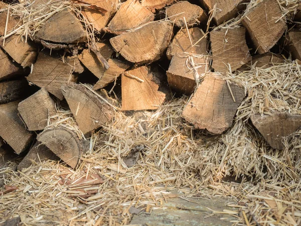 The fuel wood stacked on top of each other mixed with straw. Boards of pine, view of the end. Firewood for heating the house and kindling. Wood for the stove. Look at the stack of firewood close-up.