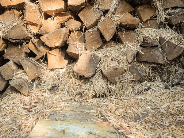 The fuel wood stacked on top of each other mixed with straw. Boards of pine, view of the end. Firewood for heating the house and kindling. Wood for the stove. Look at the stack of firewood close-up.