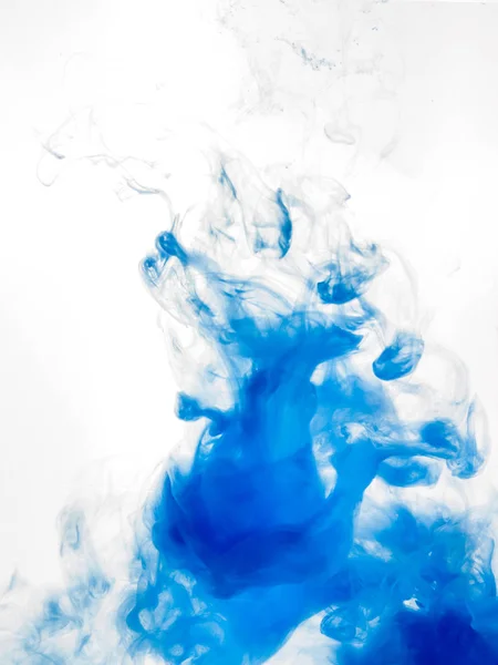 Inchiostro vorticoso in acqua isolata su fondo bianco. La vernice blu nell'acqua. Diffusione morbida di gocce di inchiostro blu in primo piano dell'acqua. Foto astratta verticale con messa a fuoco morbida, sfondo sfocato — Foto Stock