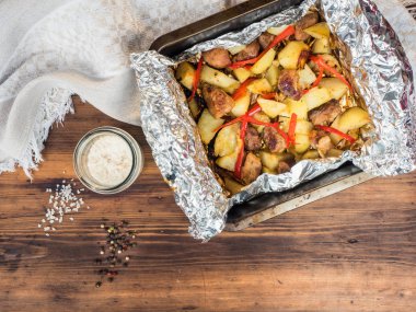 Et fırında patates ile karışık, biber, tuz kaba kumaş ve ahşap masa arka plan üzerinde. Fırın tepsisine, üstten görünüm folyo patates kızartma