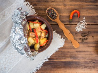 Tavuk etli patates bir seramik kase pişmiş. Arka plan eski ahşap ve kaba kumaş üzerinde ülke tarzı natürmort. Biber ve baharat, üstten görünüm bir tahta kaşıkla mensup