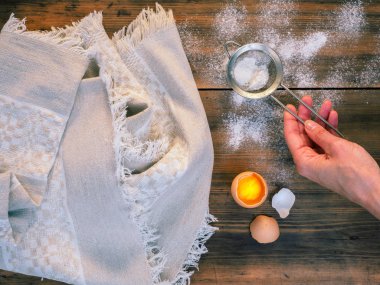 Eski ağaç ve dağınık un bir arka plan üzerine kaba kumaş kumaştan. Kadın el un sifts. Kompozisyon, rustik tarzda Üstten Görünüm