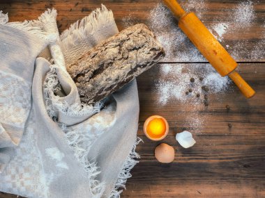 Kahverengi ekmek kırık kabuk ile eski ağacının bir arka plan üzerine kaba kumaştan bir bezle sarılmış ve un dağınık. Kompozisyon, rustik tarzda Üstten Görünüm