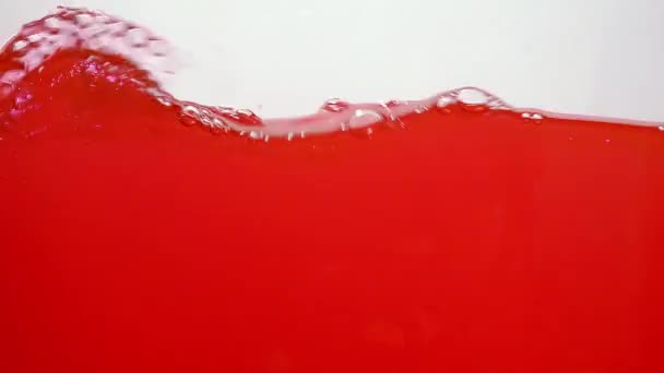 Красный поток воды движется на белом фоне. Волны с пузырьками воздуха на поверхности. Разрез воды в центре рамы. Съемка на 60 кадров в секунду, формат HD — стоковое видео