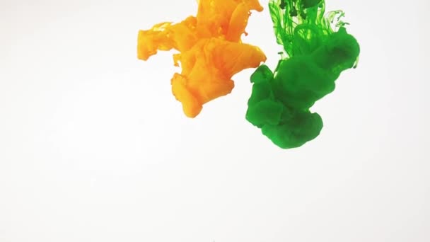 Paint moving in water, white background. Green, yellow acrylic ink swirling in water. Traces of abstract colourful clouds of paint dissolving in water, ever changing shape. Shot at 60fps, HD format. — Stock Video