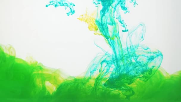 Groene en gele acrylverf wervelende in water op witte achtergrond. Inkt verplaatsen in water maken van abstracte wolken. Sporen van kleurrijke inkt oplossen in water, steeds wisselende vorm. 60fps, Hd-formaat. — Stockvideo