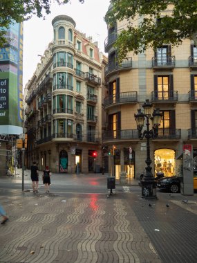 Barcelona, Spain - august 2019: crossroad in city center, long view. People walking the street, car driving. Buildings and vintage lighting column. Selective soft focus. Blurred background. clipart