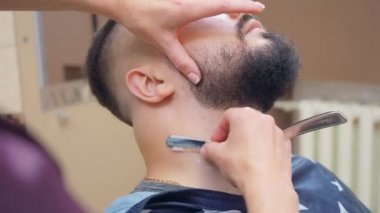 Berber traş erkek boyun açık jilet ile, yakın çekim. Berber dükkanında bir erkek. Kuaför salonunun içi. Seçici yumuşak odaklanma. Bulanık arkaplan.