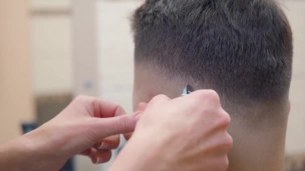 Mâles près de la nuque, gros plan. Styliste coupe les cheveux des clients avec tondeuse. Homme dans le salon de coiffure. Maître au travail chez le coiffeur. Mise au point sélective. Fond flou . — Video