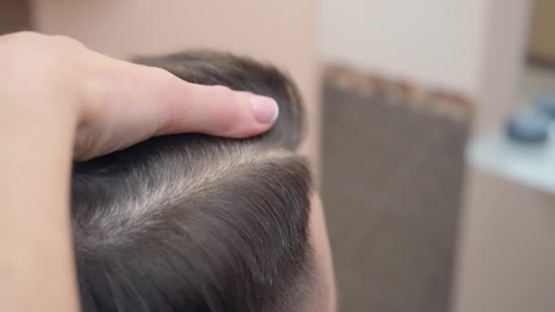 Stylists hands with open razor, close shot. Master cutting clients hair with open razor. Male in hairdressing saloon. Selective soft focus. Blurred background. — Stock Video