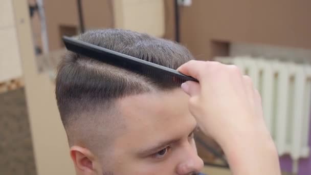 Estilista corte mans pelo con afeitadora abierta, tiro cerrado. Interior del salón de peluquería. Hombre en la peluquería. Enfoque suave selectivo. Fondo borroso . — Vídeo de stock