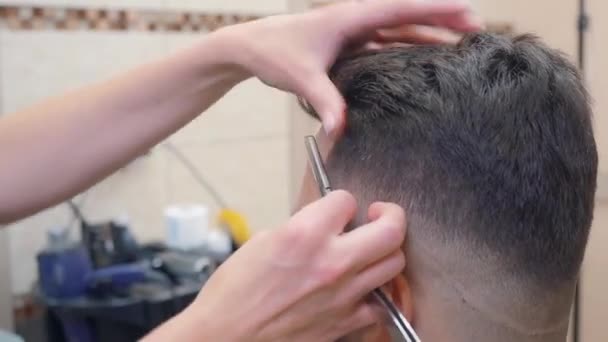 Стилист стрижет волосы на висках клиентов открытой бритвой, с близкого расстояния. Мужчина в парикмахерской. Интерьер парикмахерской. Селективный мягкий фокус. Размытый фон . — стоковое видео