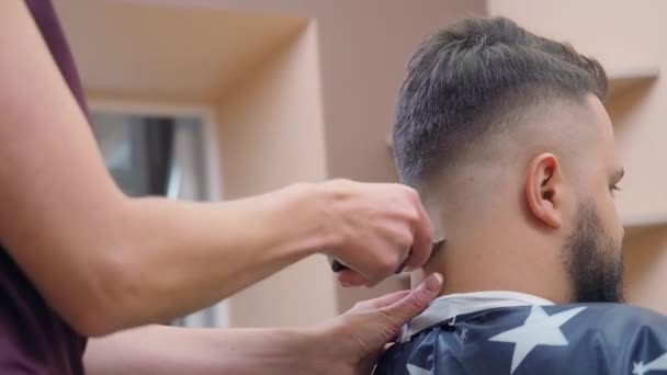 Meester aan het werk in kapsalon, dichtbij schot. Styliste knippen haar op mannetjes nek met tondeuse. Opgenomen in de kapperszaak. Selectieve zachte focus. Wazige achtergrond. — Stockvideo