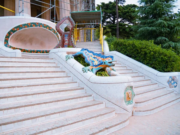 Barselona, İspanya - Ağustos 2019: Kertenkele heykeli, beyaz üst kat ve yeşil bitkiler, orta manzara. Barcelona 'daki Park Guell, Antonio Gaudi tarafından tasarlandı. Seçici yumuşak odaklanma. Bulanık arkaplan.