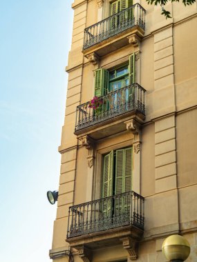 Barcelona, Spain - august 2019: medium view on beige building. Balconies of building with black railings. Selective soft focus. Blurred background.