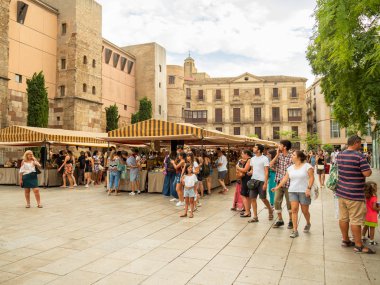 Barcelona, İspanya - Ağustos 2019: Sagrada Familia Katedrali yakınlarındaki hediyelik eşya pazarı, uzun manzara. Piyasanın yakınındaki kaldırımlı meydanda yürüyen turistler. Seçici yumuşak odaklanma. Bulanık arkaplan.