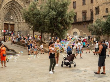 Barselona, İspanya - Ağustos 2019: Sagrada Familia Katedrali 'nin girişi, orta manzara. Tapınağa girmeden önce bir sürü turist var. Tapınağın yanındaki yeşil ağaçlar. Seçici yumuşak odaklanma. Bulanık arkaplan.