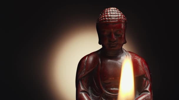 Panning střílel vedle sedícího v meditační soše Buddhy. Hořící svíčka na popředí. Dolly camera move, slowly sliding, close-up shot. — Stock video