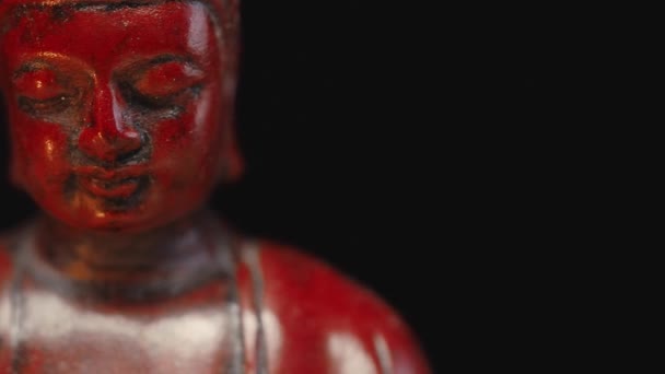 Камера Долли движется, сидя в медитационной статуе Будды. Фигура зажжена свечой на темном фоне. Панировочный выстрел слева направо, медленно скользящий, крупным планом — стоковое видео