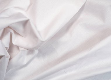 White textile, close up view, an abstract background. Texture of crumpled white fabric. Clean sheet, background for banners and wallpapers.