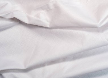 White textile, close up view. White smooth fabric, an abstract background. Cloth texture. White clean sheet, background for wallpapers, or banners.