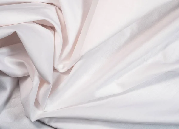 Crumpled white sheet, close up view. White textile, an abstract background. Texture of crumpled fabric. Background for banners and wallpapers. — Stock Photo, Image