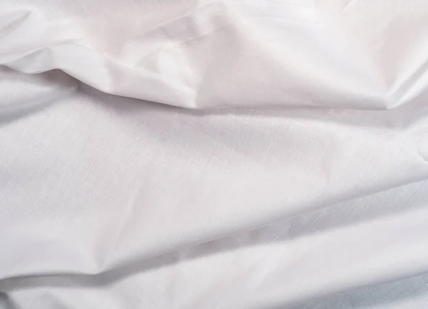 White textile, close up view. White smooth fabric, an abstract background. Cloth texture. White clean sheet, background for wallpapers, or banners.