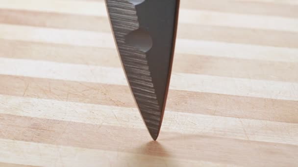 Lâmina escura de faca de cozinha, tiro de perto. Ponto de faca girando sobre mesa de madeira. Fundo abstrato. Foco suave seletivo. Fundo desfocado . — Vídeo de Stock