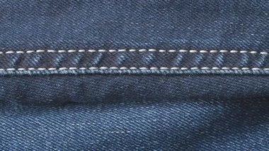 Kot pantolonun kumaşı, yakın çekim. Dolly 'nin pamuk kalıbı. Kot pantolon deseni. Dikişler ve dikişler yakın. Soyut arkaplan.