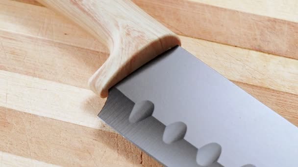 Cuchillo de cocina de mango de madera a punta de cuchillo, tiro cerrado. Dolly tiro de cuchillo tendido en la mesa en la cocina, fondo abstracto. Textura de mesa de madera . — Vídeos de Stock