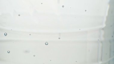 Plastik şişede baloncuklar, yakın çekim. Bir şişe masa suyu, yaklaşın. Kabarcıklar çıkıyor, soyut bir arkaplan. Statik kamera. Seçici yumuşak odaklanma. Bulanık arkaplan.