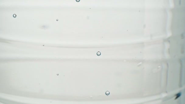 Flasche Tafelwasser, Nahaufnahme. Mineralwasserblasen, abstrakter Hintergrund. Statische Kamera. Flasche mit Minialwasser aus nächster Nähe. Selektiver weicher Fokus. Unklarer Hintergrund. — Stockvideo