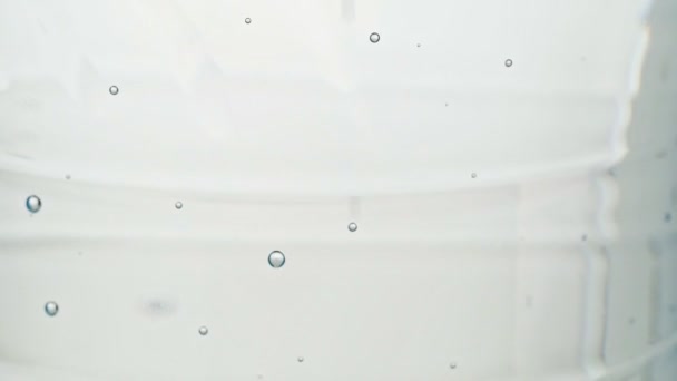 Bubbels in plastic fles, dichtbij schot. Fles tafelwater, sluiten. Bubbels lopen omhoog, abstracte achtergrond. Statische camera. Selectieve zachte focus. Wazige achtergrond. — Stockvideo