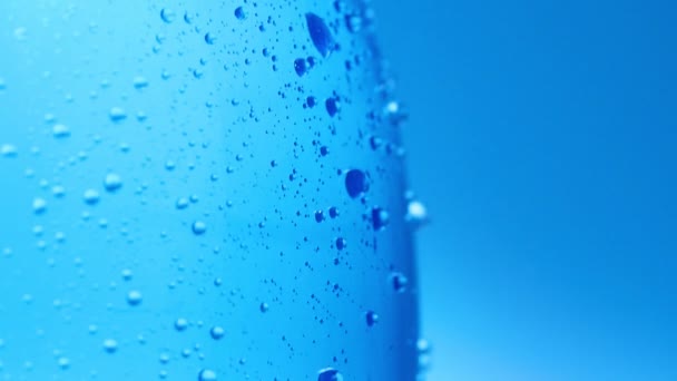 Dolly shot of bottle of table water covered with condensation. Water drops on plastic bottle, close shot. Abstract blue background. Selective soft focus. Blurred background. — Stock Video