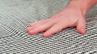 Kareli kumaşın insan eliyle sıkılması. El bir yumruğa sıkıca yapışır ve sonra açılır ve çerçeveden kaybolur. Statik kamera. Yakın çekim görünümü